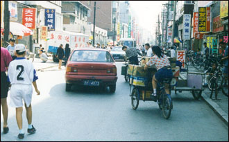 연길 시가지, 세 바퀴 자전거와 승용차, 사람이 뒤섞였다. 